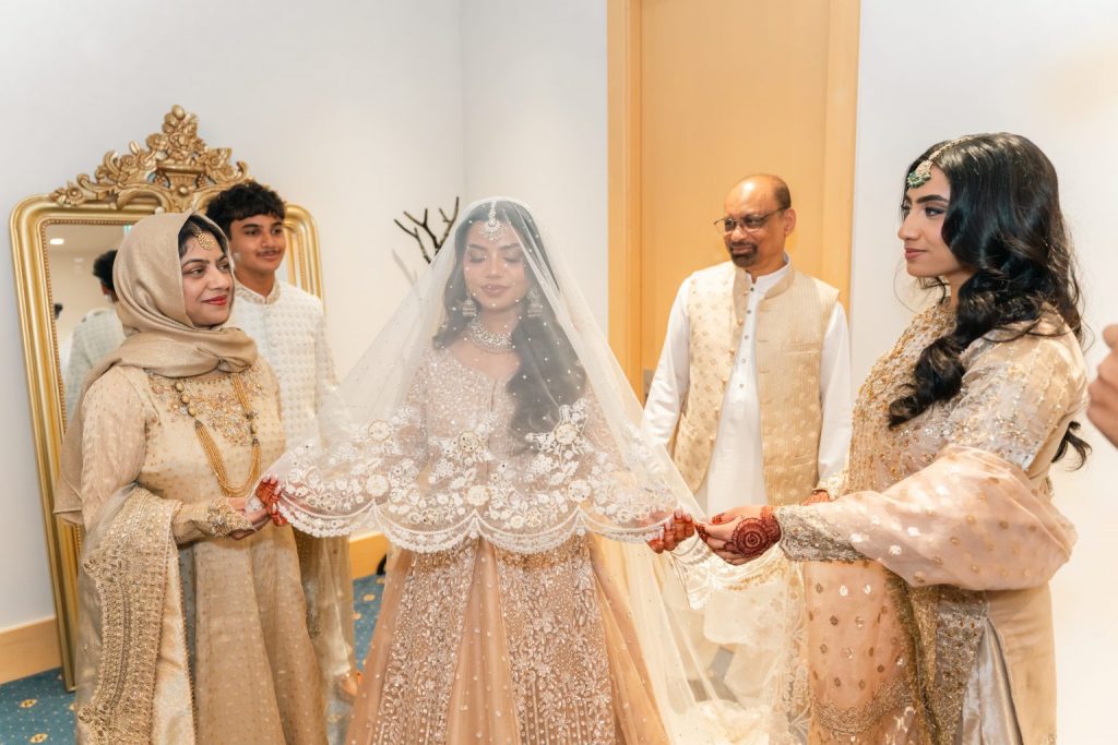 Bride with family adjusting veil during wedding preparation