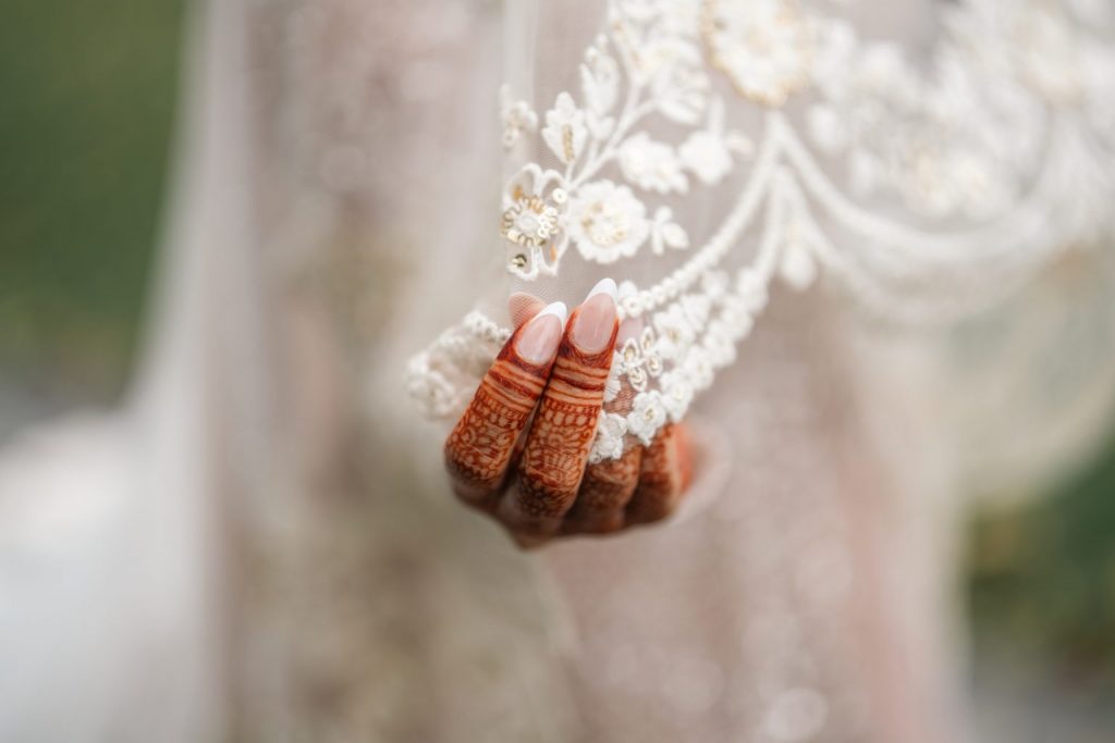 bride henna hands holding embroidered sleeve during wedding photoshoot